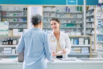 A man wearing a blue shirt talking to a pharmacist